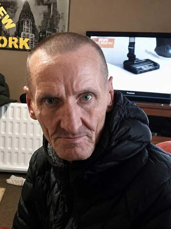 A close-up selfie of Francis Croft. He is wearing a dark jacket and looking directly at the camera, with household furnishings visible in the background.